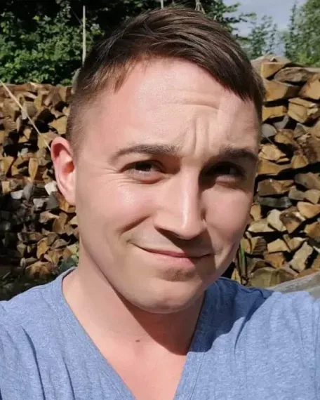Porträt von Moritz Knöfel vor gestapeltem Kaminholz